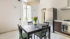 Eine moderne Küche mit Einbauofen, einem Esstisch mit Stühlen und einer Vase mit Blumen.