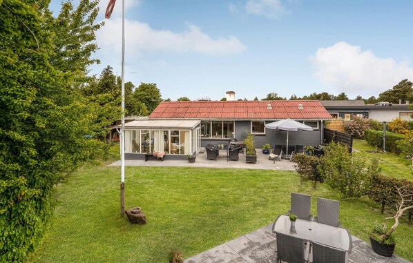 Enjoy a serene outdoor space with a patio, table, and chairs, surrounded by lush greenery and a well-maintained lawn.