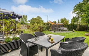 Relax in the serene outdoor patio area surrounded by lush greenery and a beautiful view.