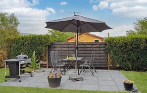Enjoy al fresco dining on the patio, surrounded by lush greenery and a grill for outdoor cooking.