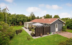 Enjoy a peaceful retreat in this charming two-story home with a patio and lush green surroundings.