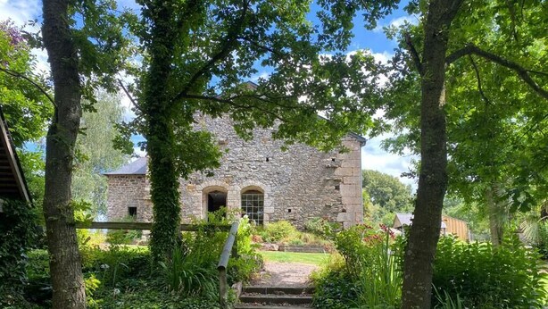 Un bâtiment en pierre avec un sentier de jardin menant à une entrée en arc de cercle.