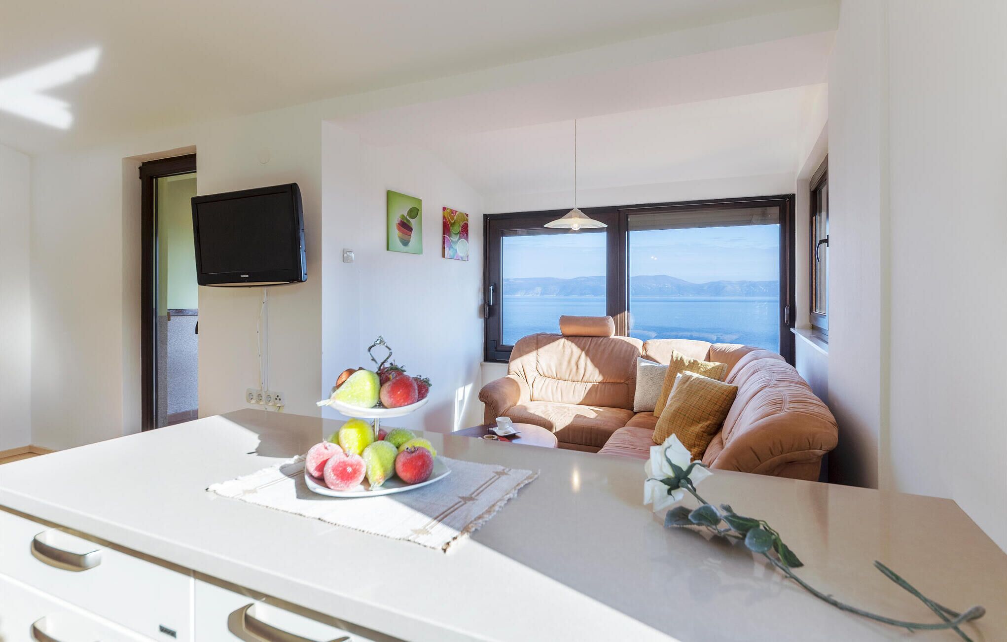 Een moderne woonkamer met een bank gericht op een groot raam met uitzicht op een wateroppervlak.