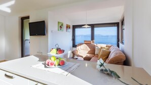 A modern living room with a sofa facing a large window overlooking a body of water. - Nice apartment in Labin with house sea view (Labin)