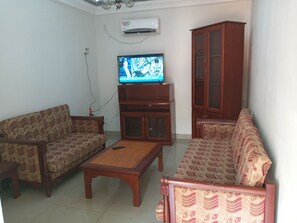 A living room with patterned sofas, a wooden coffee table, and a television on a stand.