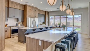 A modern kitchen with wooden cabinets, a large island, and bar stools. - New | Family Reunions | Corporate Retreats | Private Pool |  Sleeps 23 (Washington)