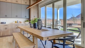 A modern kitchen with wooden cabinets, a large dining table, and a view of a mountainous landscape through large windows. - New | Family Reunions | Corporate Retreats | Private Pool |  Sleeps 23 (Washington)