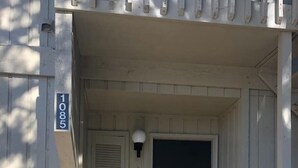 A front porch with a dark door, a light fixture above it, and a mailbox on the left. - 1085 Cozy 1 Bedroom Condo on Mobile Bay (Daphne)