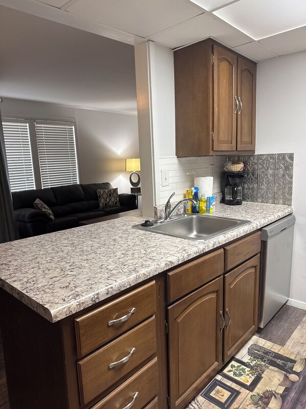 A kitchen with wooden cabinets, a granite countertop, and a dishwasher.
