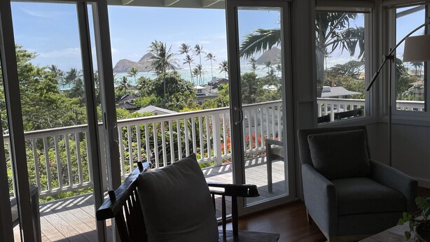 Habitación con vistas a un paisaje tropical, con palmeras y una montaña.