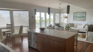 Una cocina moderna con una isla central, armarios de madera y una zona de comedor con mesa y sillas.