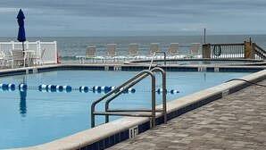 Een zwembad met uitzicht op de oceaan, een terras met ligbedden en een badmeesterstand.