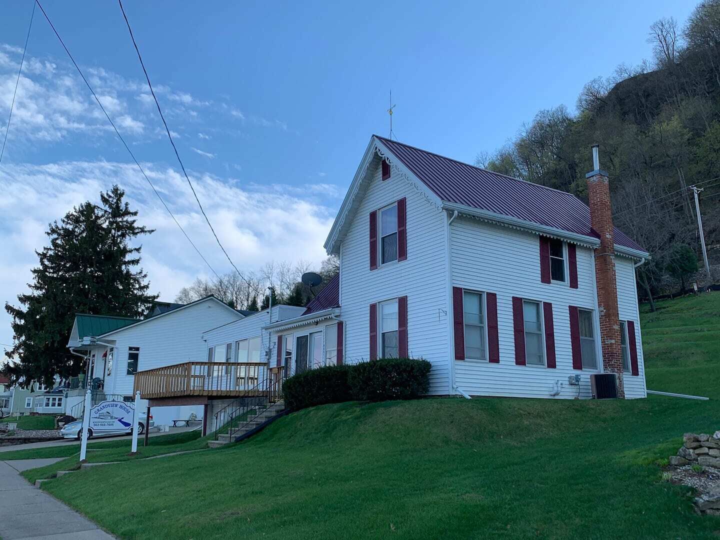 A two-story house with a red roof, white siding, and a chimney.