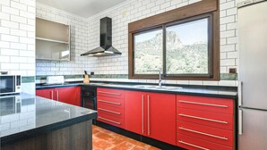 A modern kitchen with red cabinets, a black countertop, and a window with a mountain view. - Stunning home in El Jaral (El Jaral)