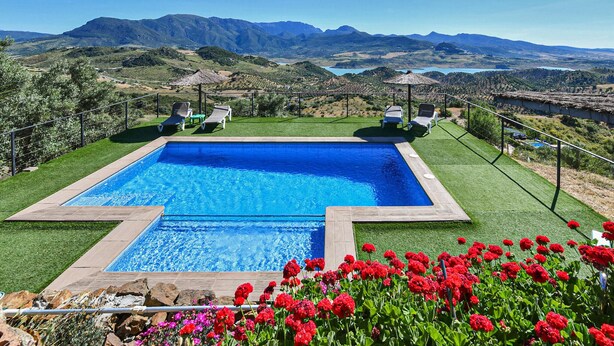A rectangular pool with a wooden deck, surrounded by green artificial grass and red flowers. - Stunning home in El Jaral (El Jaral)