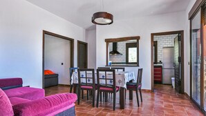 A dining area with a table set for four, surrounded by chairs. There is a sofa with a pink cover in the foreground. - Stunning home in El Jaral (El Jaral)