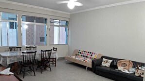 A living room with a dining table, chairs, a sofa, and a ceiling fan. - 3 Bedroom Apartment Facing Itararé Beach / SV (SP)