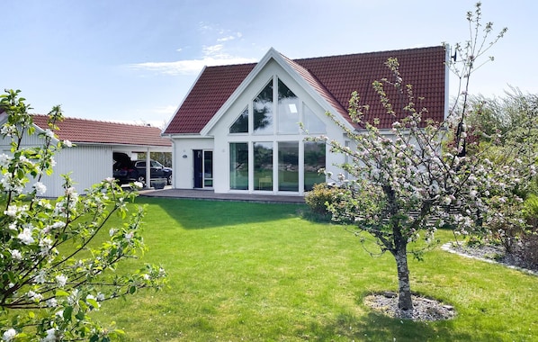 Une maison moderne avec un toit en pente, une pelouse bien entretenue et un garage.