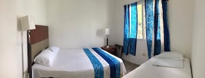 A hotel room with a bed, bedside table, lamp, and curtains. - Villas Yulli (Tela)