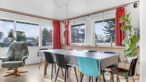 A dining area with a table, chairs, and a large window with red curtains. - Gorgeous home in Nexø with WiFi (Nexø)