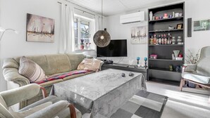A modern living room with a sofa, a coffee table, a TV, and a bookshelf. - Gorgeous home in Nexø with WiFi (Nexø)