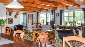 A cozy room with wooden beams, a dining table, chairs, a sofa, and a fireplace. - 7 bedroom awesome home in örkelljunga (Örkelljunga)