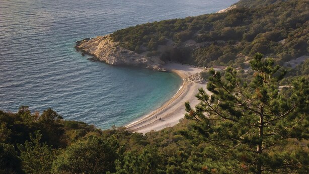 Un paysage côtier caractérisé par une plage de sable, des falaises rocheuses et une végétation luxuriante.