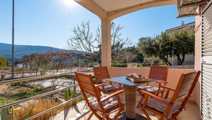 Une terrasse avec une table et des chaises, une vue sur le paysage et un panneau de signalisation indiquant un arrêt.