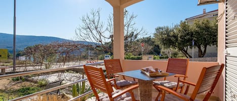 A terrace with a table and chairs, a view of the landscape, and a stop sign.