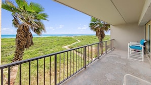 A balcony with a view of the beach, a chair, and a railing. - Beach FRONT Hideaway for your Fun in the Sun!️ (South Padre Island)