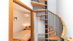 A spiral staircase with wooden steps and black railings, leading to a bedroom with a bed and a nightstand. - Gorgeous home in Vinisce with house sea view (Vinisce)