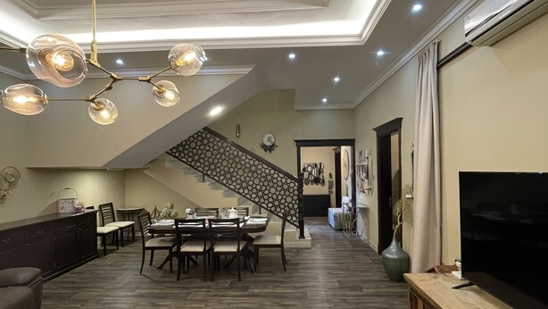 Amplia sala de estar con comedor, una escalera y un televisor a la derecha.