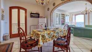 A dining area with a table set for four, surrounded by chairs, a chandelier, and a view of the sea. - Nice apartment in Giardini Naxos with WiFi (Giardini Naxos)