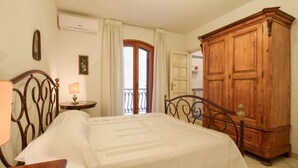 A bedroom with a bed, a wooden wardrobe, a nightstand with a lamp, and a window with curtains. - Nice apartment in Giardini Naxos with WiFi (Giardini Naxos)