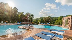 Ein Poolbereich mit mehreren Pools, Liegestühlen und einer natürlichen Landschaft im Hintergrund.