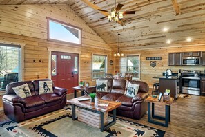 Ein gemütliches Cabin-Interieur mit Holzbalkendecke, Ledersofas, einem Essbereich und einer Küche.