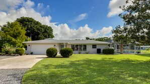 A single-story house with a garage, a well-maintained lawn, and a large tree to the right. - Canal Home to Gulf Completely Renovated, Large Pool, come to Serenity Retreat!!! (Englewood)