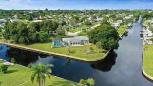 A residential area with a canal, houses, and greenery. - Canal Home to Gulf Completely Renovated, Large Pool, come to Serenity Retreat!!! (Englewood)