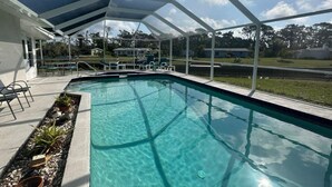 A swimming pool with a covered area, clear blue water, and a view of the surrounding landscape. - Canal Home to Gulf Completely Renovated, Large Pool, come to Serenity Retreat!!! (Englewood)