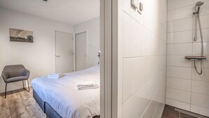 Ein Hotelzimmer mit Bett, Stuhl, Duschbereich und Tür.