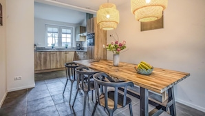A modern kitchen with wooden cabinets, a dining table with chairs, and two hanging pendant lights.