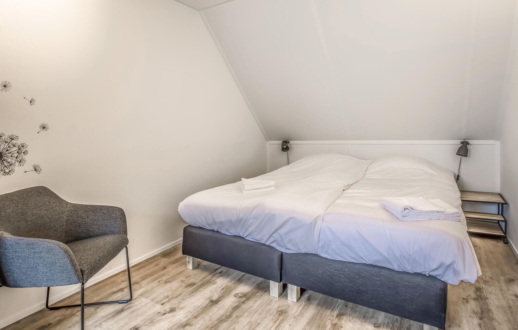 A bedroom with a bed, a chair, and a wall decoration.
