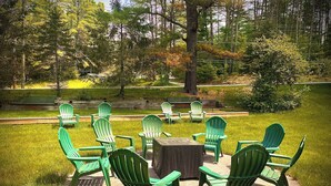 An outdoor seating area with green Adirondack chairs arranged around a wooden table.