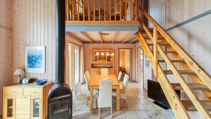 A wooden cabin interior with a dining area, a kitchen, a fireplace, and a staircase. - Nice home in Rechlin with sauna (Rechlin)