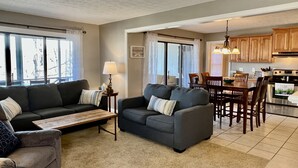 A living room with a sofa, coffee table, and a dining area with a table and chairs. - Woodson Bend-Golf, Pool Restaurant& More-Near Burnside W/Lake View - First Floor (Bronston)