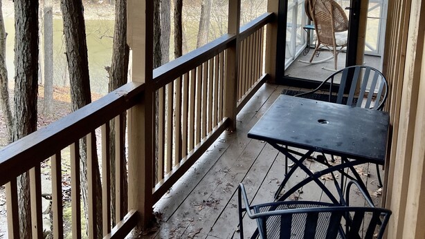 A covered outdoor area with a wooden deck, a table, and two chairs. - Woodson Bend-Golf, Pool Restaurant& More-Near Burnside W/Lake View - First Floor (Bronston)