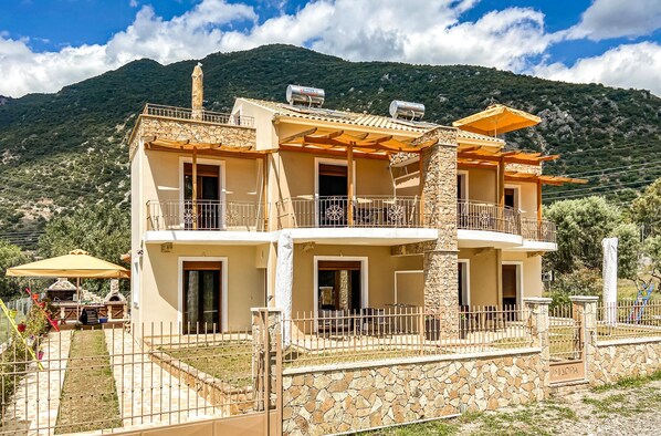 A two-story building with balconies, stone walls, and a mountainous backdrop. - 1 bedroom stunning apartment in Nafpaktos (Nafpaktos)