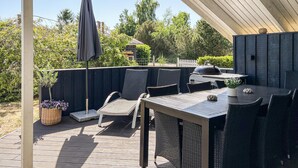 Un patio exterior con mesa y sillas, una parrilla y un área cubierta.