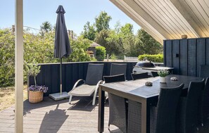 Eine Terrasse im Freien mit Tisch und Stühlen, einem Grill und einem überdachten Bereich.