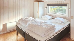 Un dormitorio con cama, armario y ventana con vistas a zonas verdes.